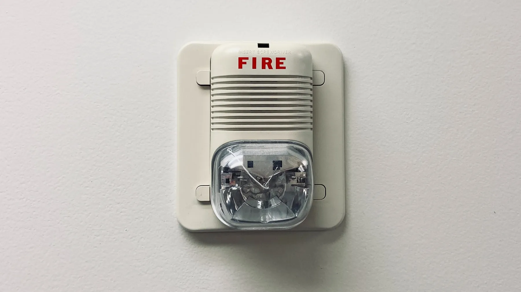 A white fire detector on drywall